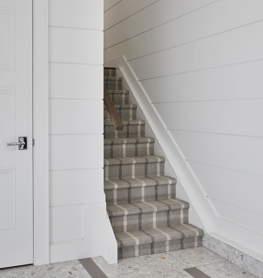 staircase with shiplap walls and grey plaid carpeting